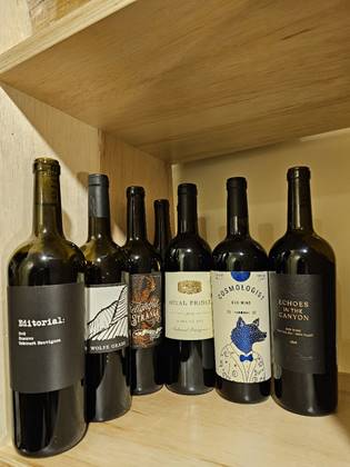 A group of wine bottles on a shelf
Description automatically generated